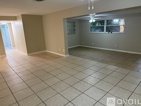 A spacious room with tiled flooring and a window overlooking a tree.