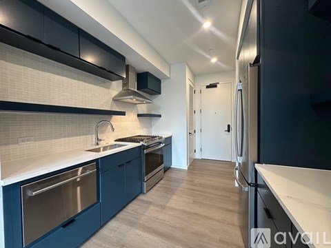 A modern kitchen with dark blue cabinets and stainless steel appliances.
