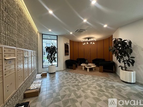 A spacious living room with a black sofa, a wooden coffee table, and a large window.