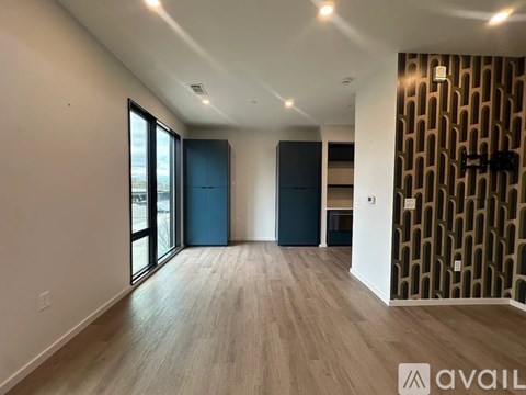 A spacious room with wooden flooring and a wall with a geometric pattern on the right side.