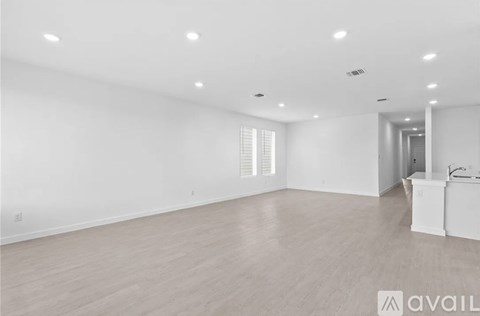 A spacious room with wooden flooring and white walls.