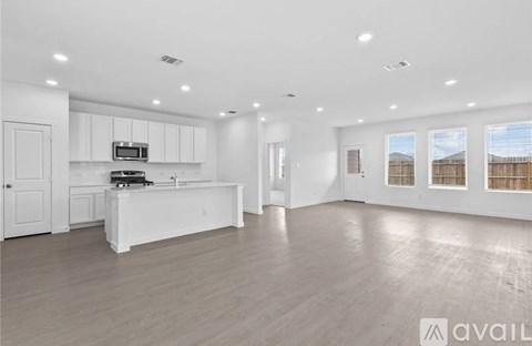 A spacious kitchen with white cabinets and a wooden floor.