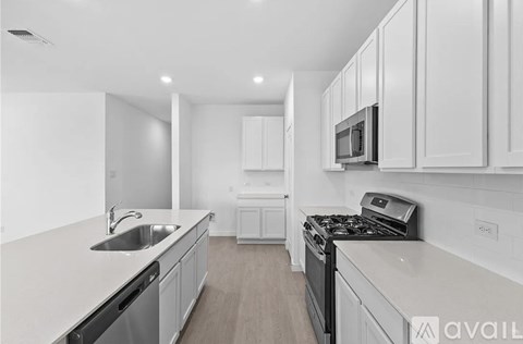 A modern kitchen with white cabinets and stainless steel appliances.