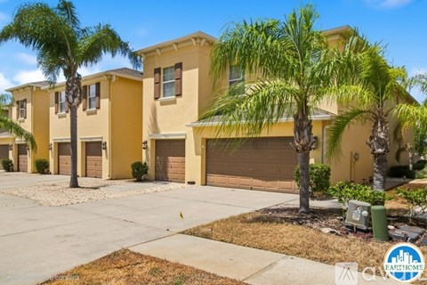 A row of houses with palm trees in front.