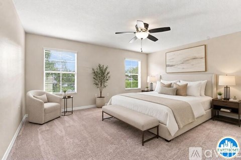 A bedroom with a bed, chair, and ceiling fan.
