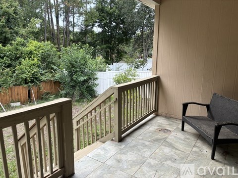A balcony with a bench and a view of a wooded area.