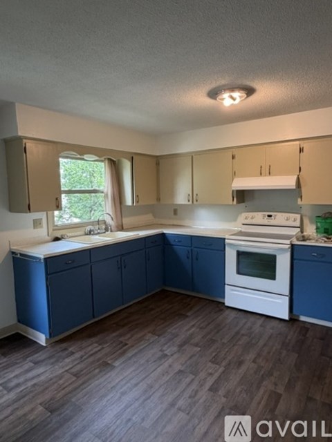 A kitchen with blue cabinets and a white stove top oven.