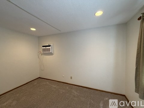 A room with a carpeted floor and a ceiling fan with a light.