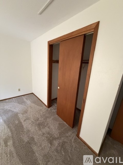 A room with a carpeted floor and a wooden door.