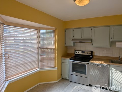 A kitchen with yellow walls and white cabinets.