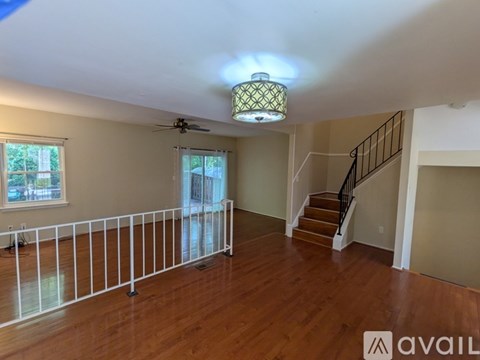 A room with a fan, stairs, and a window.