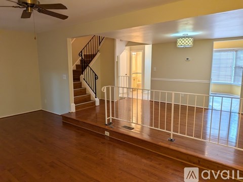 A living room with a staircase and a ceiling fan.