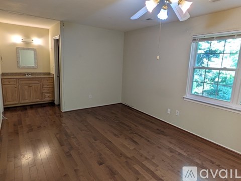 A room with wooden flooring and a window with a view of trees.