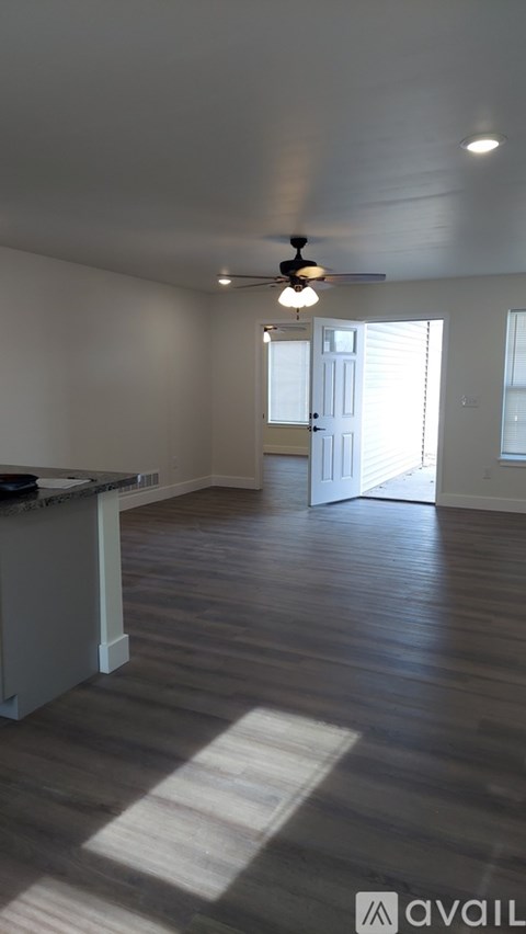 A room with a ceiling fan and a door leading to another room.