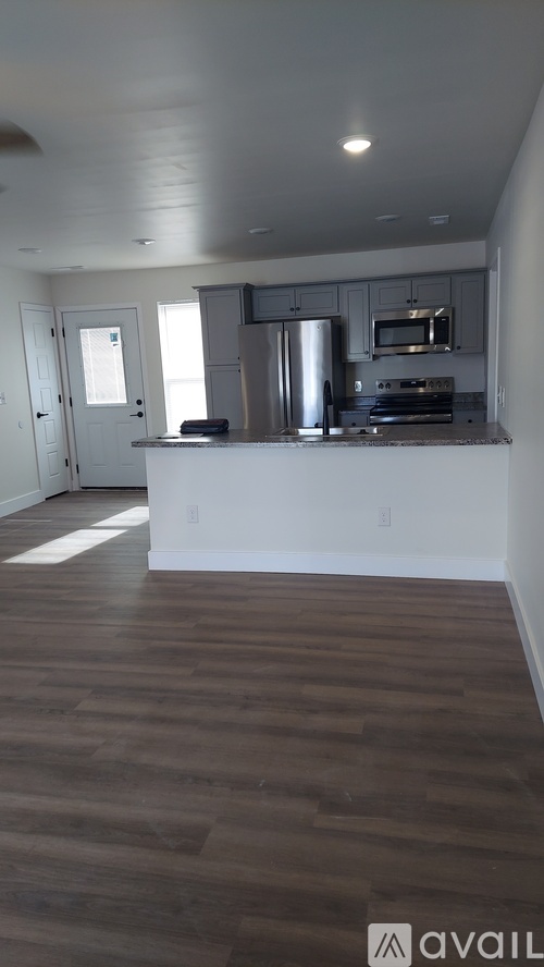 A kitchen with a white counter and wooden floors.