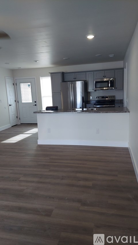 A kitchen with a white counter and wooden floors.