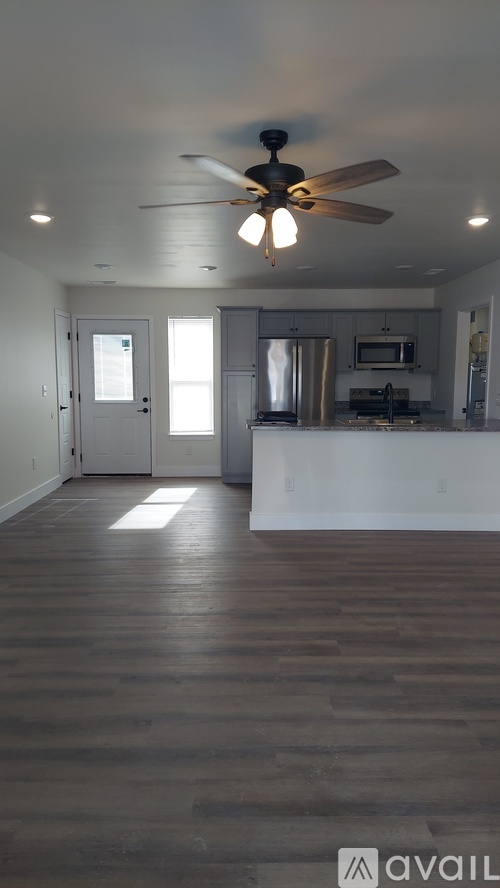 A spacious room with a ceiling fan and wooden flooring.