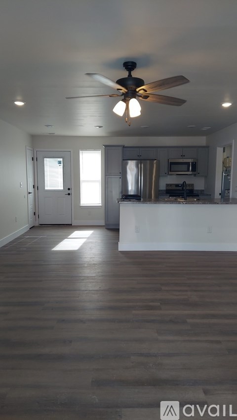 A spacious room with a ceiling fan and wooden flooring.