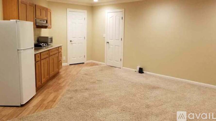 A kitchen area with a refrigerator, cabinets, and a microwave.