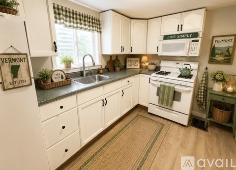 A kitchen with white cabinets and a Vermont sign on the fridge.