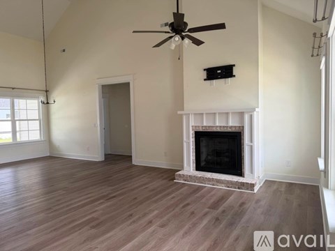 A living room with a fireplace and a ceiling fan.