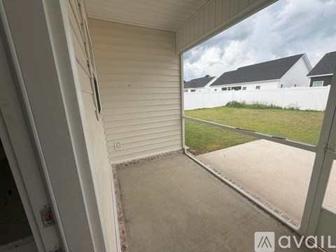A balcony with a view of a grassy area and houses.