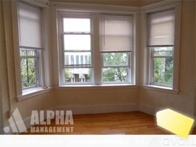 A room with three windows and wooden floors.