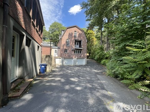 A narrow alley with a blue trash bin and a building on the left.