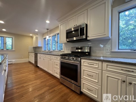 A kitchen with white cabinets and a wooden floor.