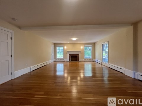 A spacious room with wooden floors and a fireplace.