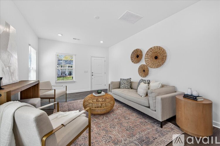 A living room with a sofa, a chair, a table, and a window.