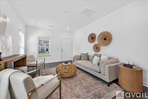 A living room with a sofa, a chair, a table, and a window.
