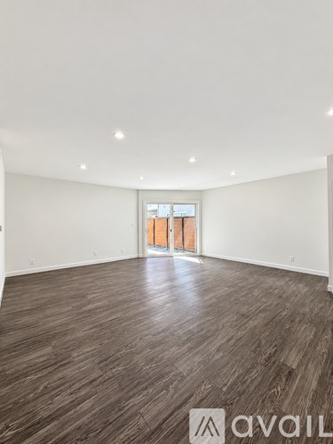 A spacious room with wooden flooring and a large window.