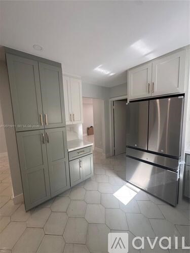 A kitchen with a stainless steel refrigerator and cabinets.