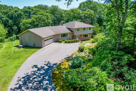 A house with a driveway and trees in the background.