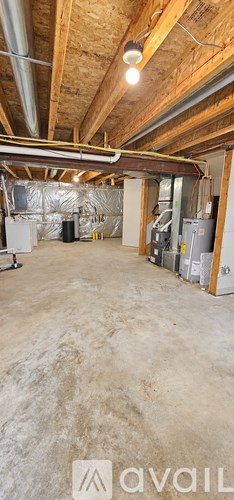 A spacious attic room with wooden beams and insulation on the walls.