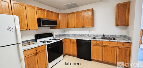 A kitchen with wooden cabinets and a black dishwasher.