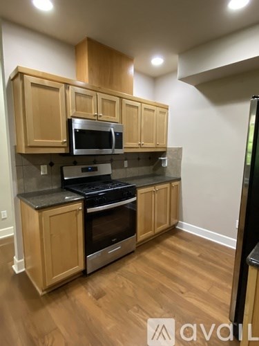 A kitchen with wooden cabinets and a black refrigerator.