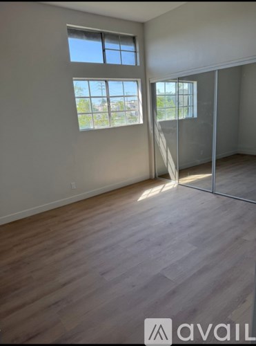 A room with wooden flooring and two windows.