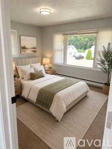 A bedroom with a bed, nightstand, and window.