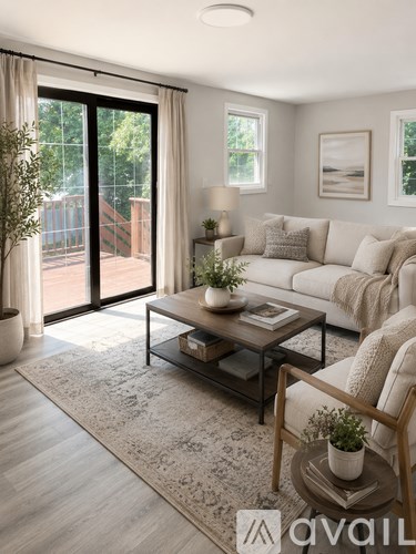 A living room with a white couch, a coffee table, and a large window with a view of the backyard.