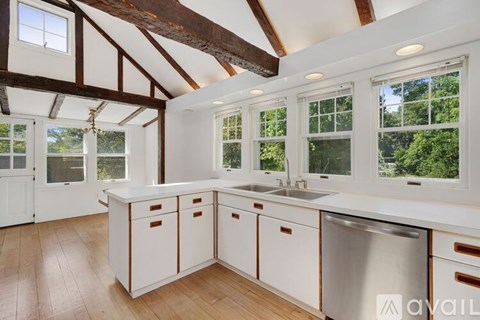 A kitchen with white cabinets and a wooden floor.