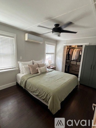 A bedroom with a bed, a ceiling fan, and a window with blinds.