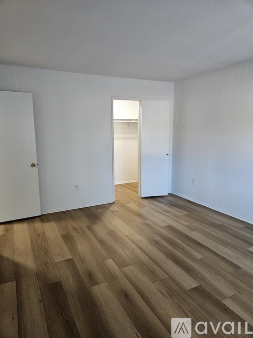A room with wooden flooring and white walls.