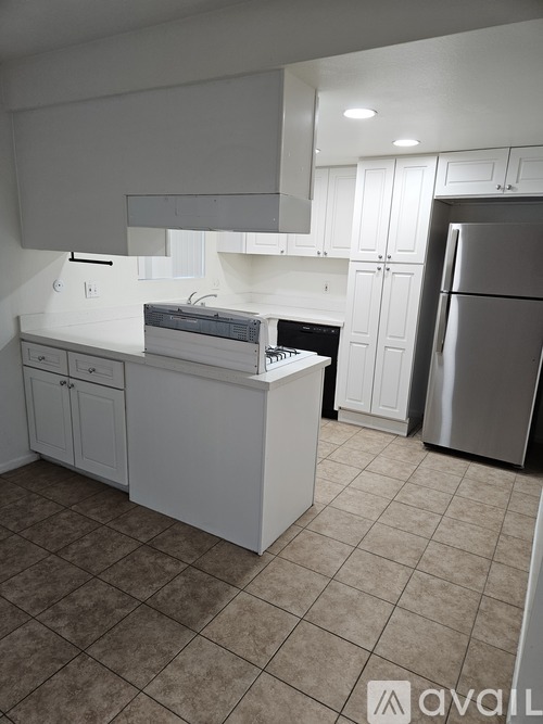 A kitchen with white cabinets and a refrigerator.