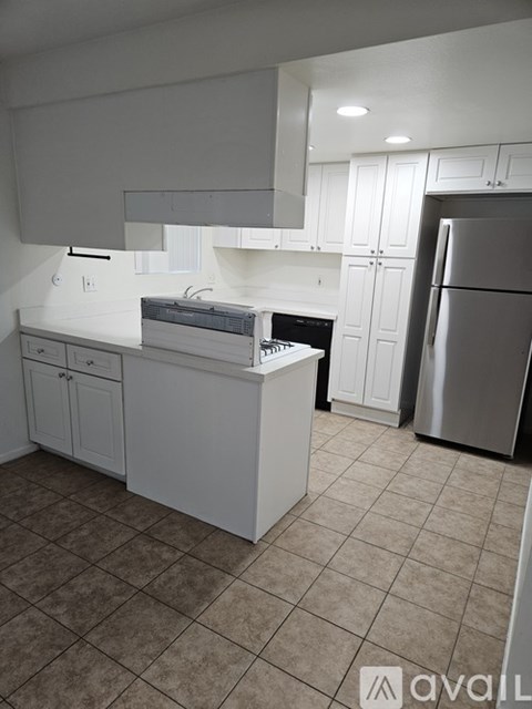A kitchen with white cabinets and a refrigerator.