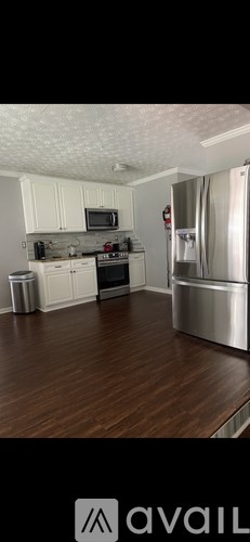 A kitchen with white cabinets and a wooden floor.