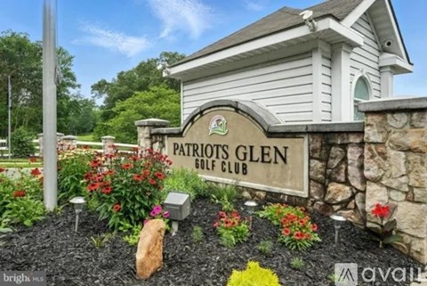 A sign for the Patriots Glen Golf Club is displayed in front of a building.