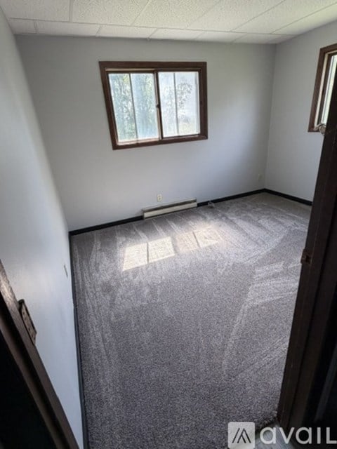 A room with a window and a carpeted floor.