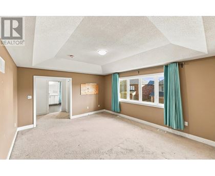 A spacious room with a carpeted floor and a large window with green curtains.